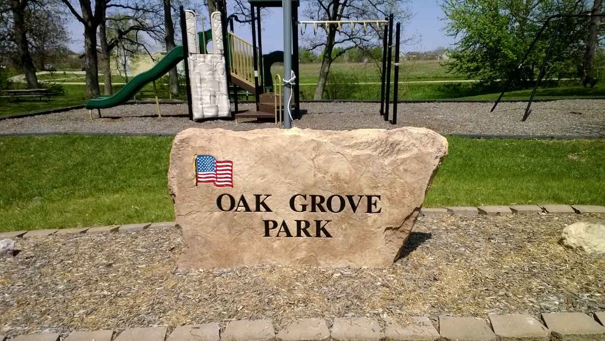 Oak Grove Park entrance sign with playground behind.